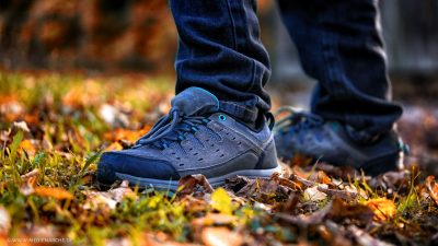 Nahaufnahme der Füße eines jungen Mannes, auf einer von Herbstblättern bedeckten Wiese.